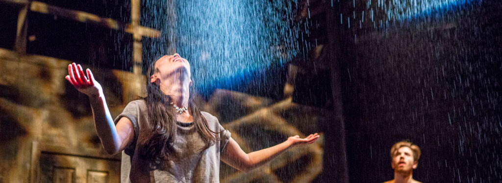 Performers onstage under rain