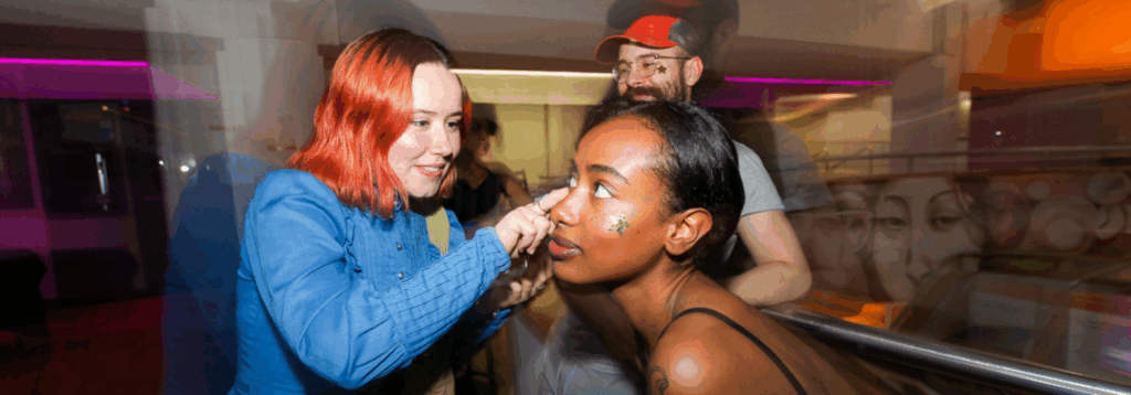 performer places gold star on team member's face